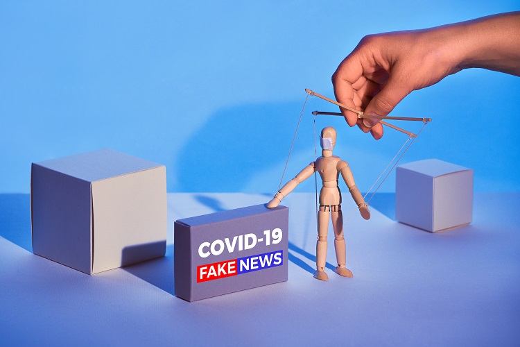 Covid19 novel coronavirus rumors. Sinister hand control wooden puppet on abstract geometric background. Box with text "COVID-19 fake news". Beware of fake news about outbreak 2019-nCoV and treatment